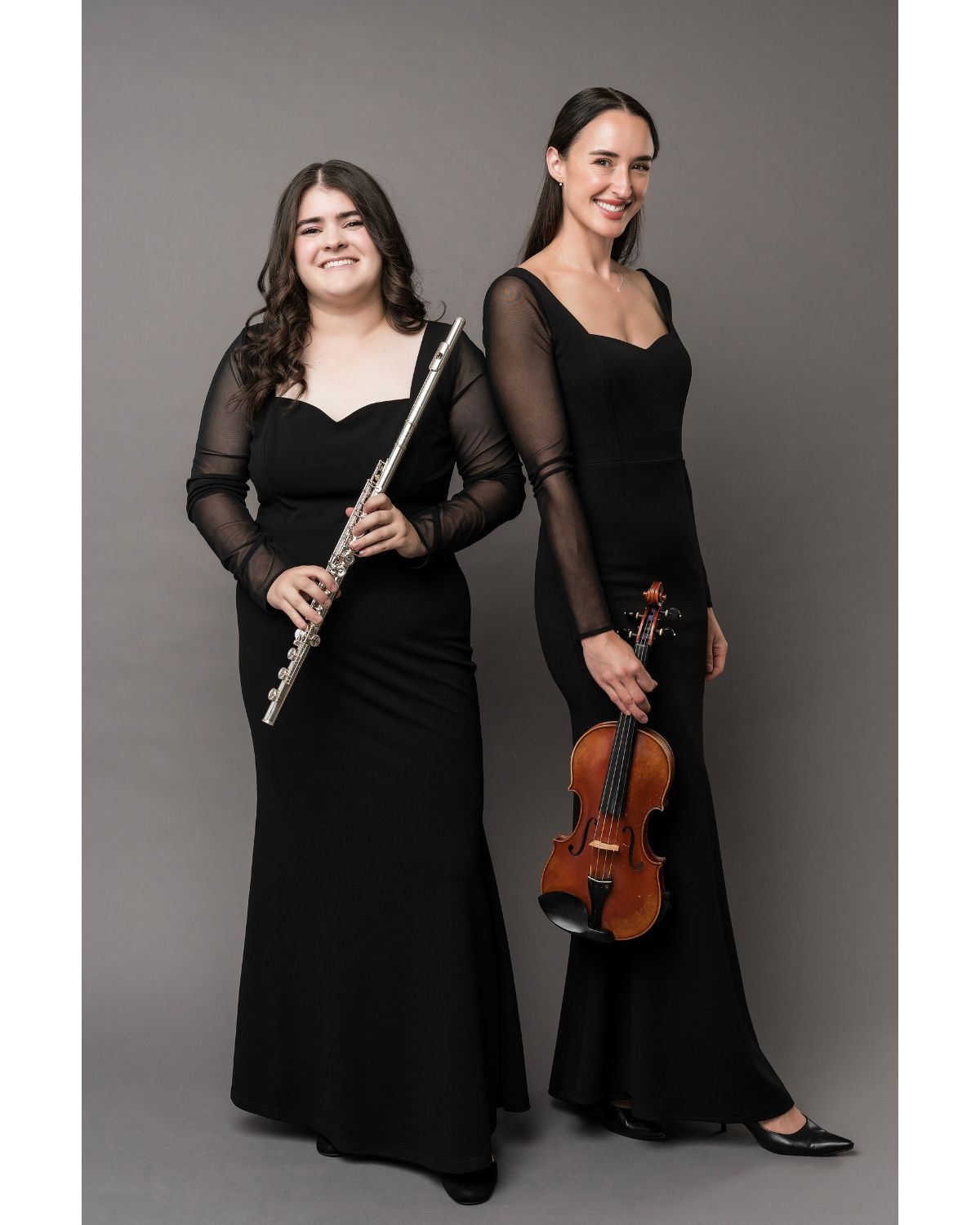 Two musicians in concert black dresses holding a flute and violin 