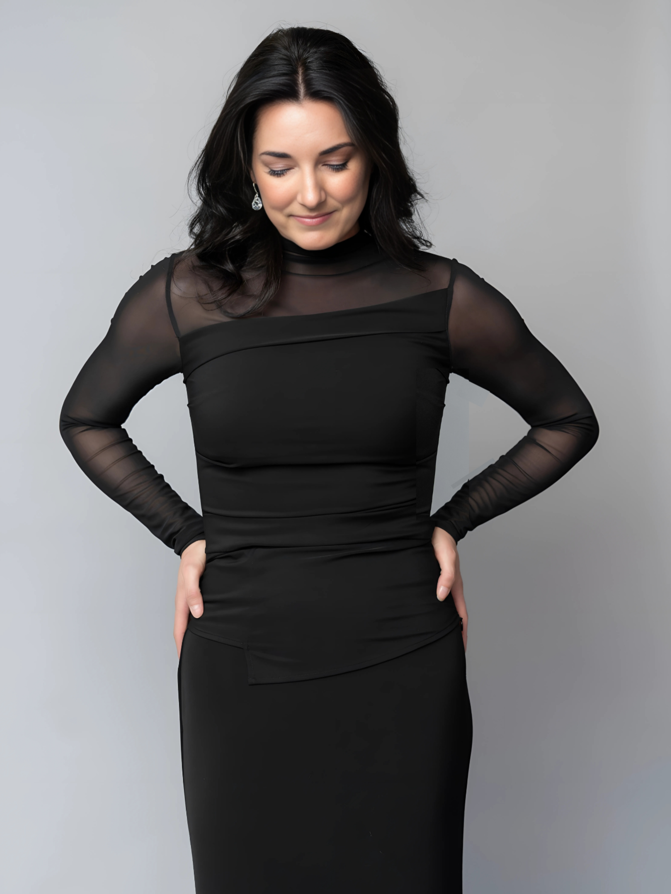Woman wearing a concert black dress with sheer sleeves and formal black skirt